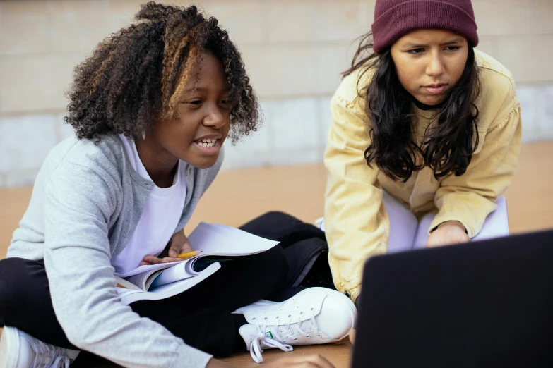 two girls sitting on the ground looking at a laptop, by Jessie Algie, trending on pexels, varying ethnicities, teaching, cardboard, avatar image