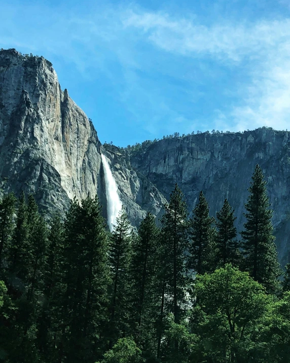 a mountain with a waterfall in the middle of it, trees in the background, lgbtq, thumbnail, profile photo