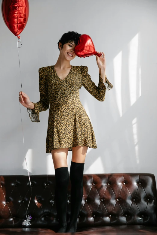 a woman standing on a couch holding a heart shaped balloon, over-knee boots, curated collections, the dress\'s lower, wearing animal skin clothing