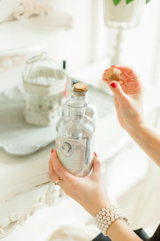 a woman holding a bottle in front of a mirror, by Julia Pishtar, unsplash, on a white table, vintage theme, detailed product shot, moonshine cybin