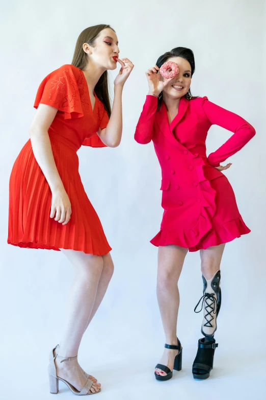 a couple of women standing next to each other, an album cover, by Gavin Hamilton, pexels, wearing a red dress, pink and orange, red shoes, ruffles