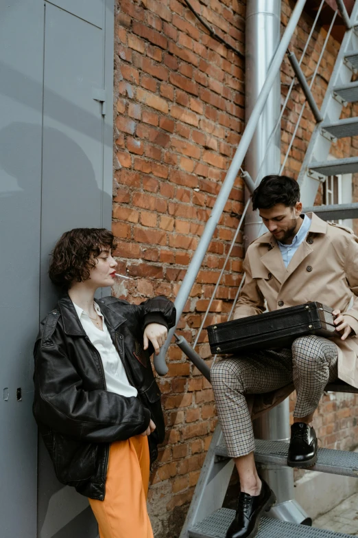 a woman standing next to a man on a set of stairs, an album cover, by Emma Andijewska, pexels contest winner, holding a briefcase, friends, roleplay, boys