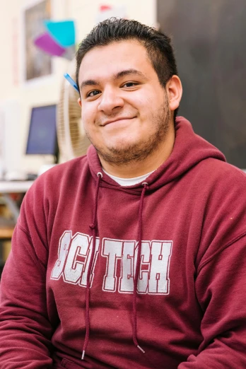 a man sitting in front of a laptop computer, a portrait, featured on reddit, maroon and white, hispanic, high school, proud smirk