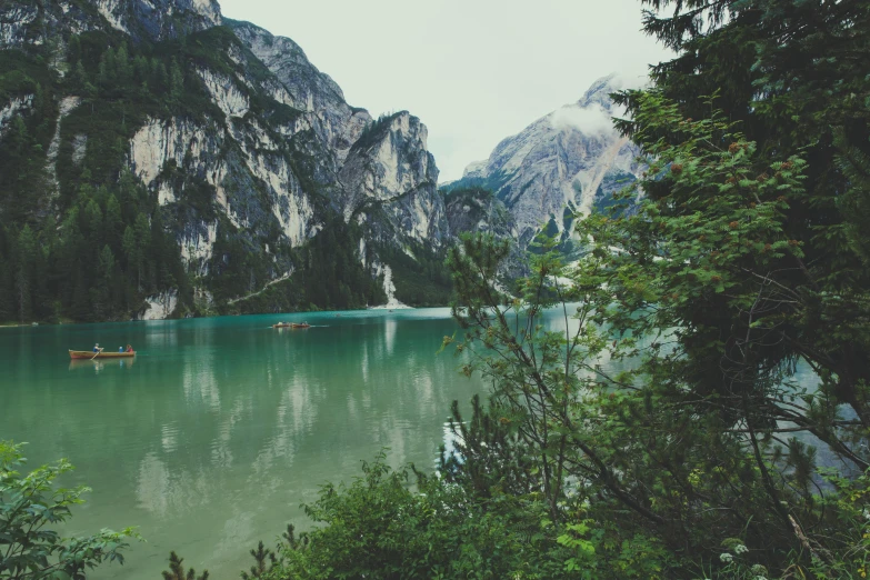 a couple of boats floating on top of a lake, pexels contest winner, renaissance, solo hiking in mountains trees, teal aesthetic, vintage photo, greenery