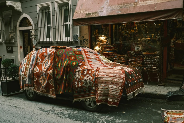 a covered car parked on the side of a street, pexels contest winner, hurufiyya, oriental carpets, mixture turkish and russian, in style of joel meyerowitz, aztec street fashion