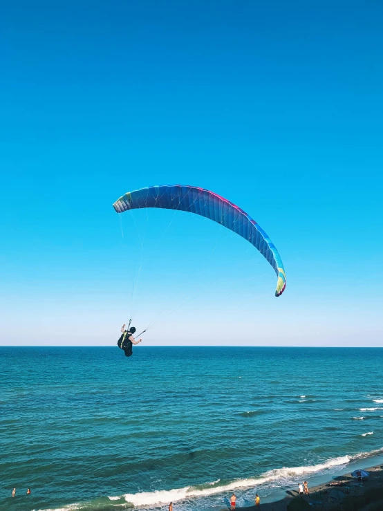 a person parasailing over the ocean on a sunny day, pexels contest winner, hurufiyya, on dune, picton blue, large screen, hunting