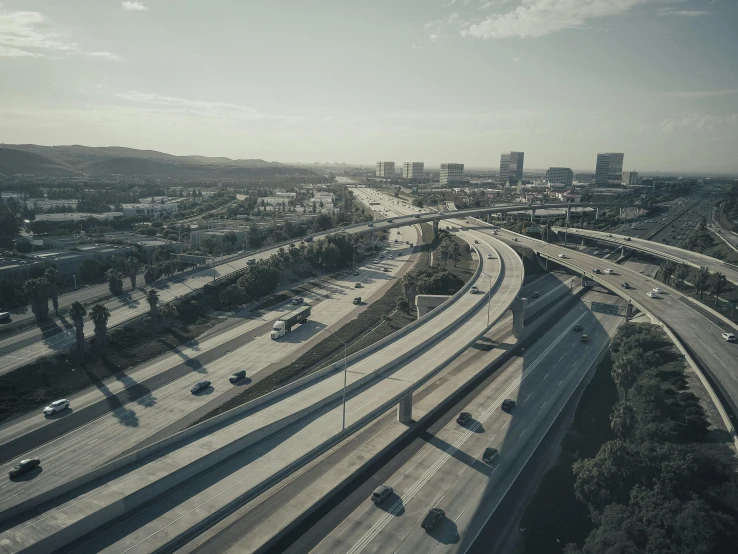 a freeway filled with lots of traffic next to tall buildings, a matte painting, unsplash contest winner, photorealism, overpass, mulholland drive, nadav kander, shot from drone