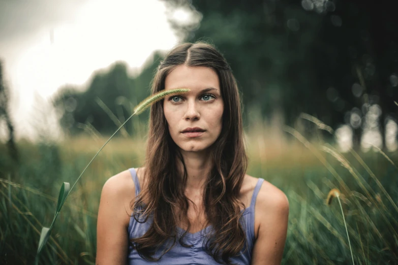 a woman standing in a field of tall grass, a portrait, by Grytė Pintukaitė, pexels contest winner, serious face, avatar image, high quality image, one raised eyebrow