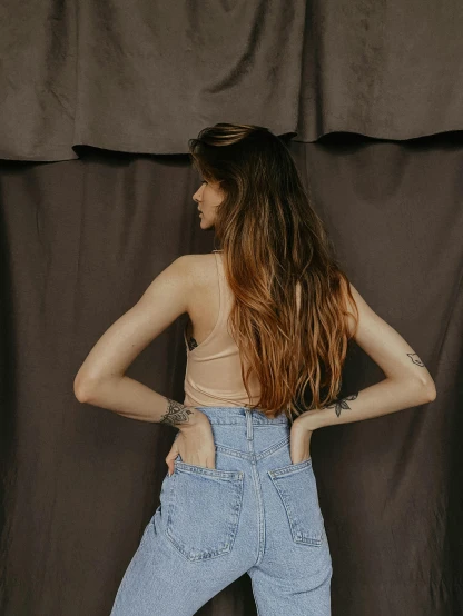 a woman standing with her back to the camera, by Pablo Rey, croptop, denim, soft vintage glow, wearing leotard