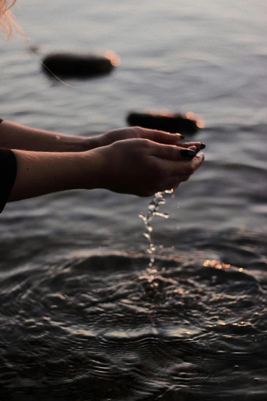 a woman washing her hands in a body of water, unsplash, late summer evening, floating crystals, phone photo, ignant