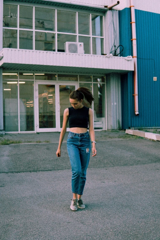 a woman walking down a street in front of a building, pexels contest winner, croptop, 90's aesthetic, ( ( ( wearing jeans ) ) ), portrait of sanna marin