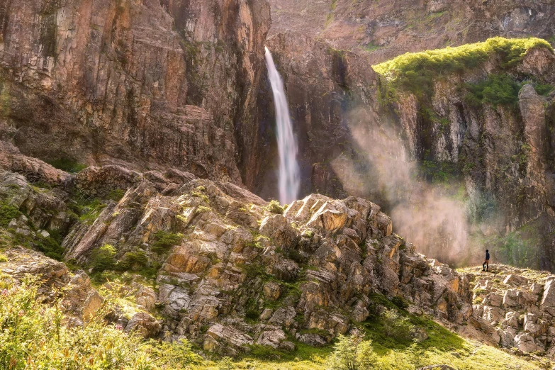 a man standing in front of a waterfall, by Muggur, pexels contest winner, hurufiyya, “ aerial view of a mountain, rivendell, in socotra island, waterfall falling down