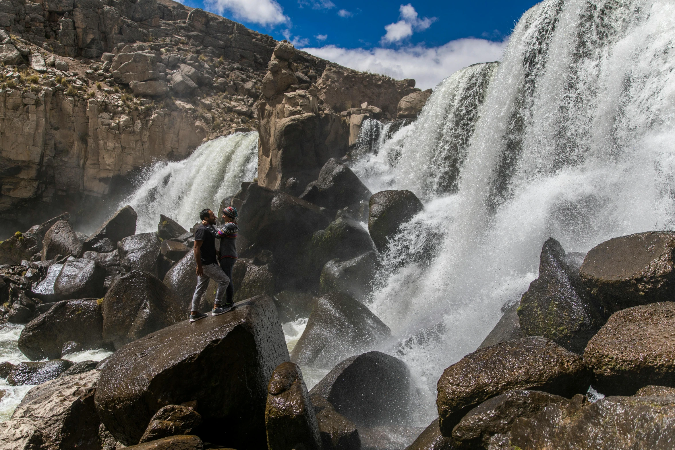 two people standing in front of a waterfall, by Terese Nielsen, pexels contest winner, hurufiyya, chile, extreme panoramic, rocks falling, thumbnail