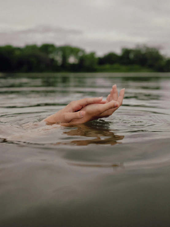 a person swimming in a body of water, with fingers