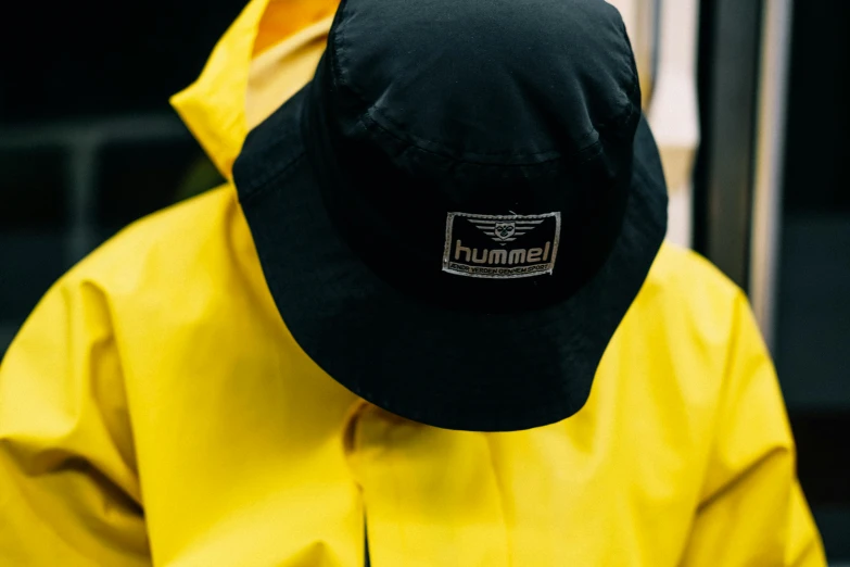 a person wearing a yellow jacket and a black hat, by Nina Hamnett, unsplash, hurufiyya, closed visor, detailed product shot, humble, met collection