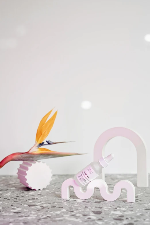 a pair of scissors sitting on top of a table, an abstract sculpture, by Lucette Barker, flamingo, bottle, papercraft, skincare