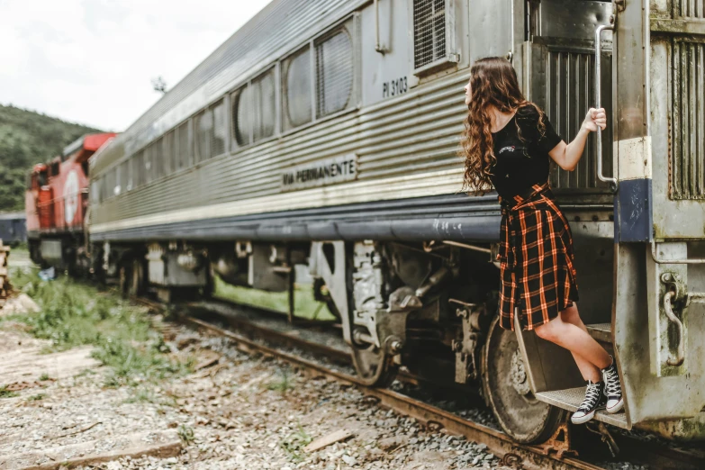 a woman leaning on the side of a train, by Joe Bowler, pexels contest winner, plaid skirt, 🚿🗝📝, profile image, full body model