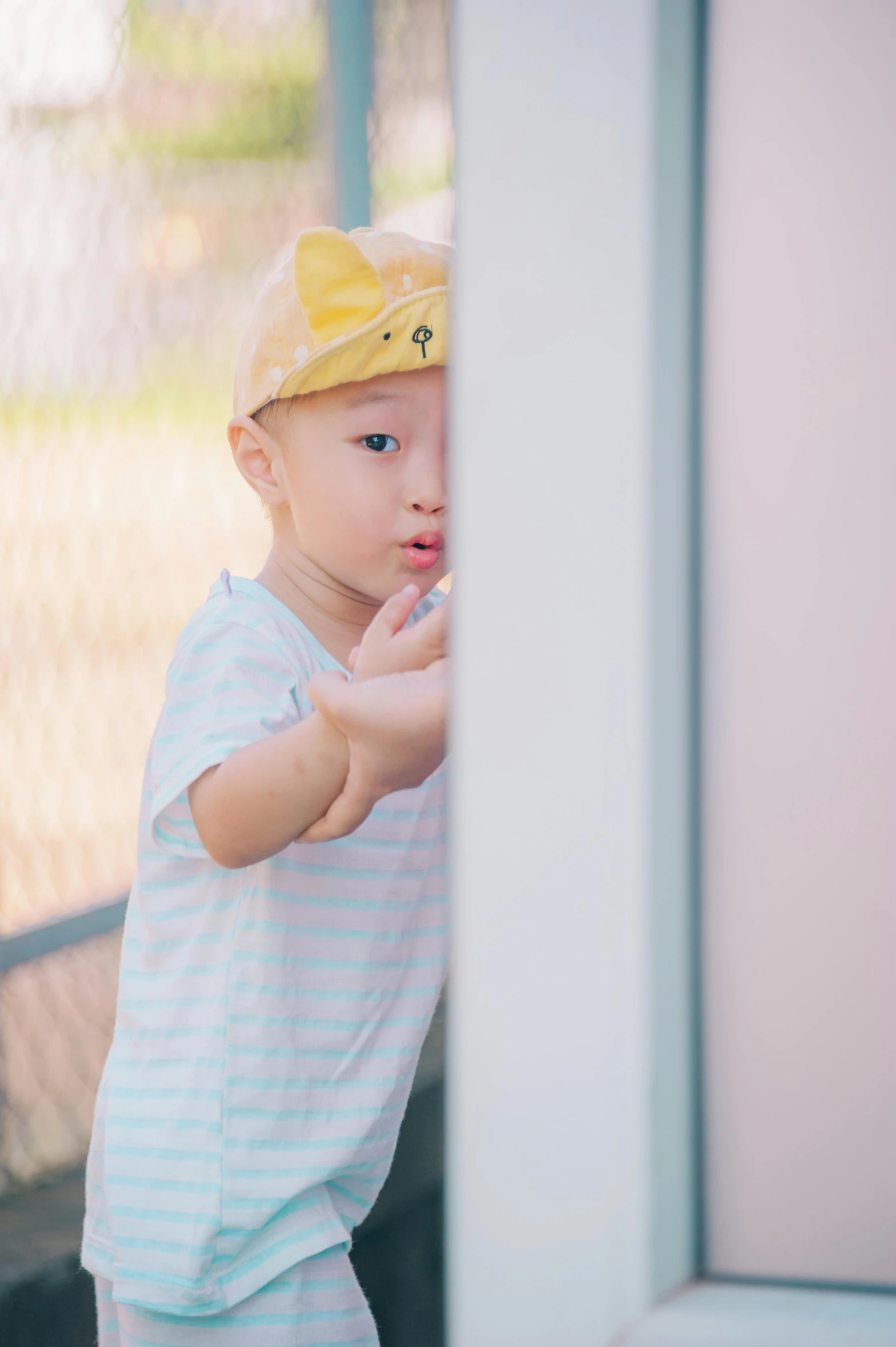 a little boy that is standing in front of a door, inspired by Yu Zhiding, pexels contest winner, yellow cap, soft shade, spying, young cute wan asian face