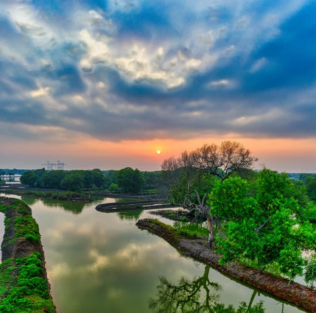 a river running through a lush green forest, by Sudip Roy, pexels contest winner, hurufiyya, sunset panorama, indore, baotou china, bright sky