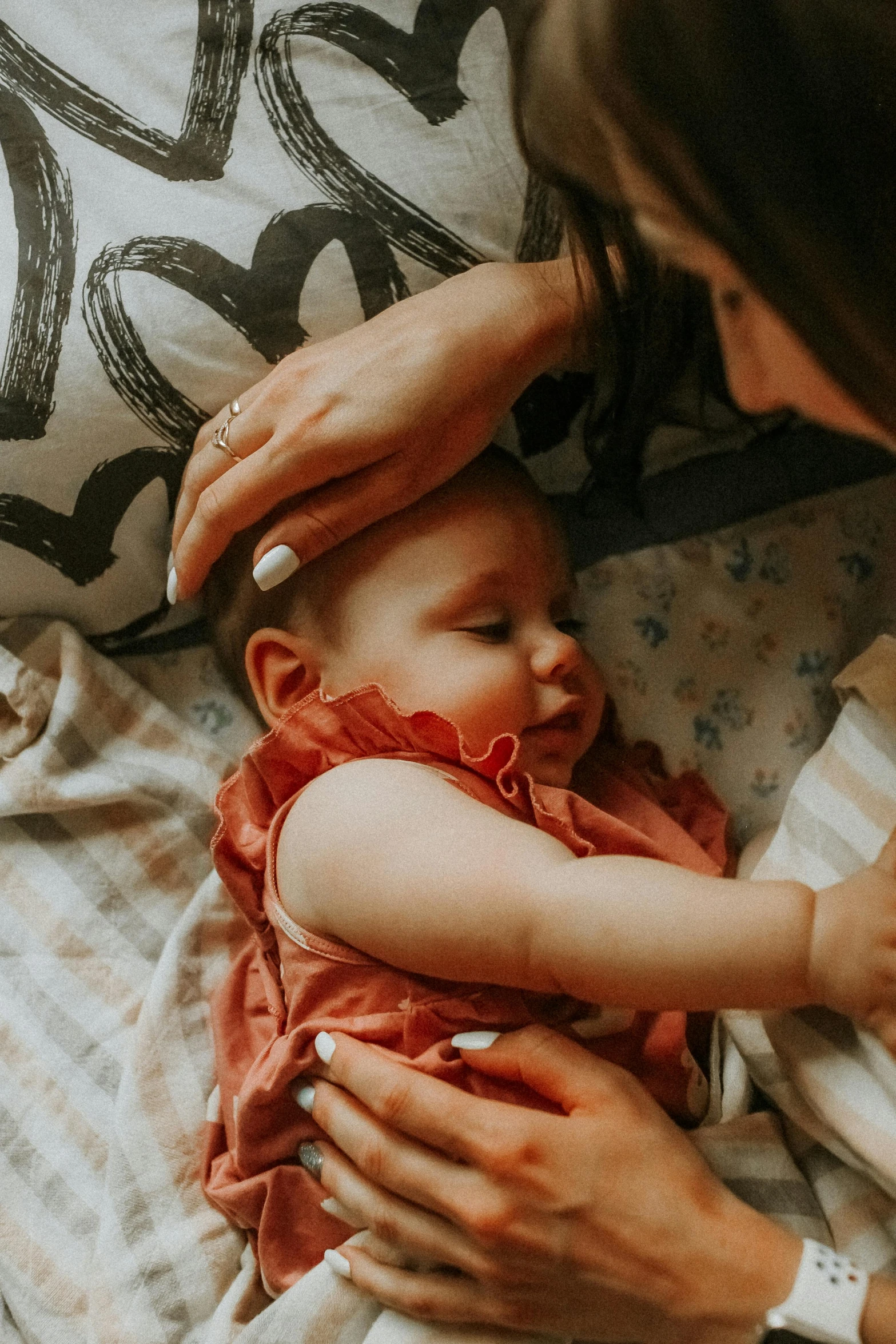 a woman holding a baby on top of a bed, pexels contest winner, resting head on hands, partially cupping her hands, looking down from above, seasonal