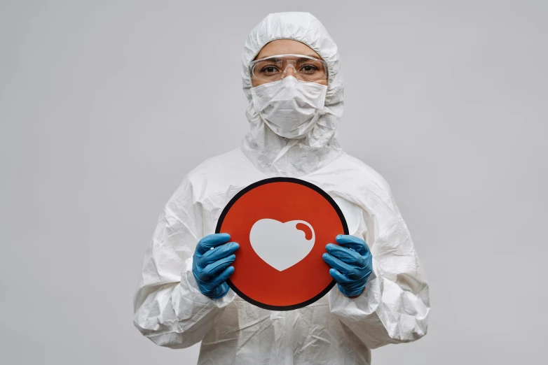 a man in a hazmat suit holding a heart sign, by Adam Marczyński, pexels contest winner, plasticien, all enclosed in a circle, processor, portrait of a female pathologist, on a gray background