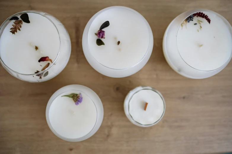 a group of candles sitting on top of a wooden table, inspired by Marina Abramović, renaissance, herbs, glossy white, from above, inside a glass jar