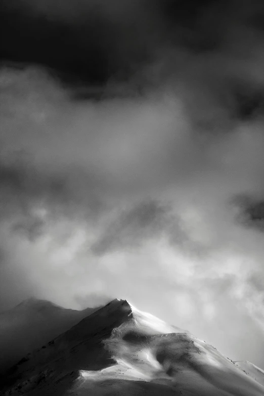 a black and white photo of a snow covered mountain, inspired by Ansel Adams, minimalism, surrounded in clouds and light, deep colours. ”, dramatic lightin, portrait of tall