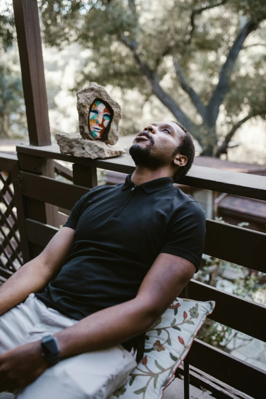 a man that is laying down on a bench, african god mask, in a garden, in a cabin, portrait featured on unsplash