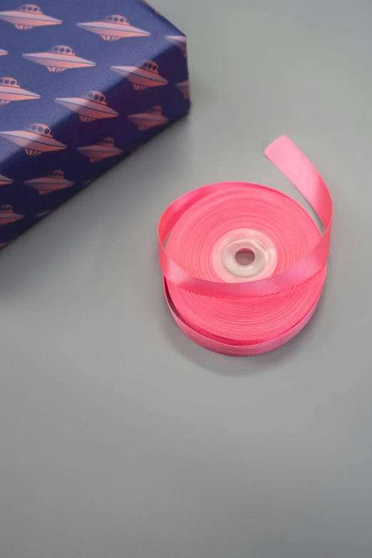 a pink ribbon next to a blue gift box, a picture, by Doug Ohlson, pexels contest winner, happening, coral red, close up shot from the side, risograph, product display photograph