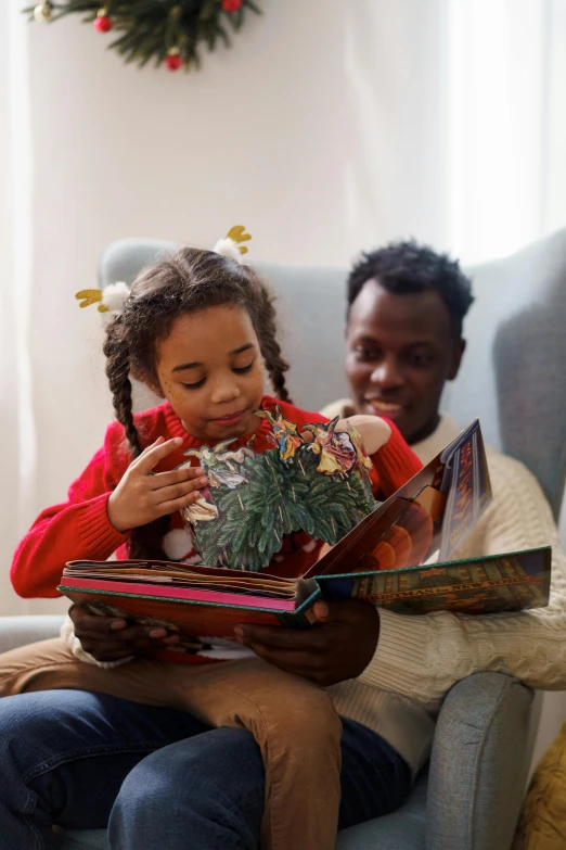 a little girl sitting in a chair reading a book, pexels contest winner, folk art, father with child, light skinned african young girl, wearing festive clothing, gif