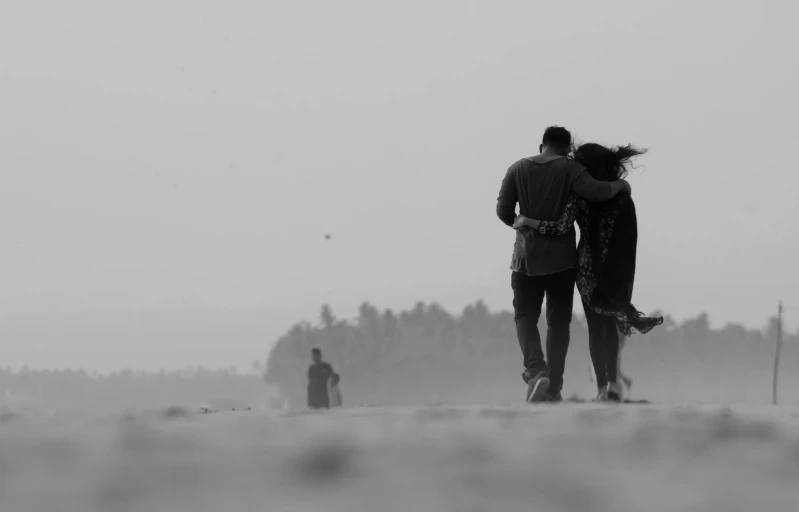 a couple of people that are standing in the sand, a black and white photo, by Max Dauthendey, pexels contest winner, romanticism, haze over the shoulder shot, distant!!, lovers, friendship