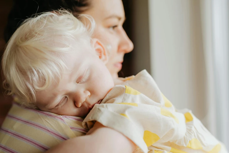 a woman holding a baby in her arms, pexels contest winner, sleeping beauty, thumbnail, looking from shoulder, toddler