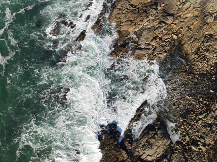 a group of people standing on top of a cliff next to the ocean, by David Donaldson, pexels, photorealism, extremely detailed water texture, close-up from above, waves crashing at rocks, rhode island