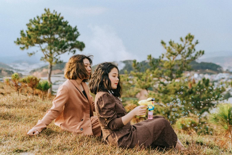 a couple of women sitting on top of a hill, trending on pexels, realism, juice, ulzzang, in style of lam manh, profile image