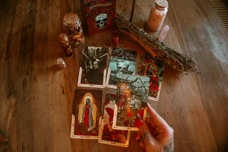 a person holding a deck of cards on a table, shrines, baba yaga, witch woman, skulls are lying underneath