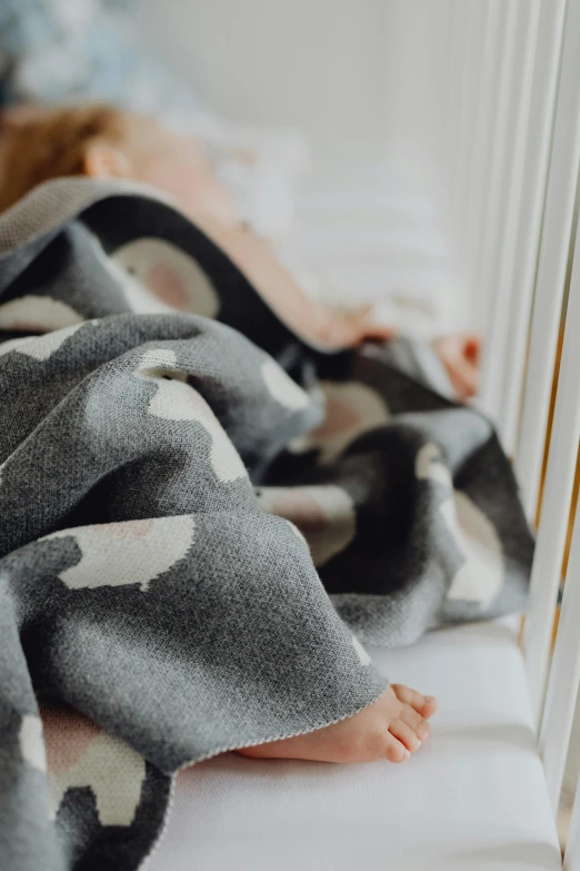 a baby laying in a crib under a blanket, a black and white photo, by Helen Stevenson, unsplash, black and white with hearts, made of wool, detailed product image, duck