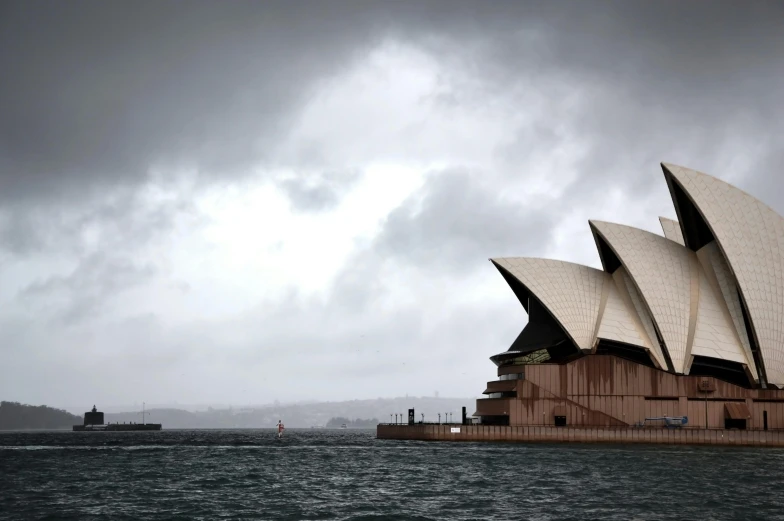 a large building sitting on top of a body of water, inspired by Sydney Carline, pexels contest winner, australian tonalism, overcast gray skies, sails, trending on dezeen, khedival opera house