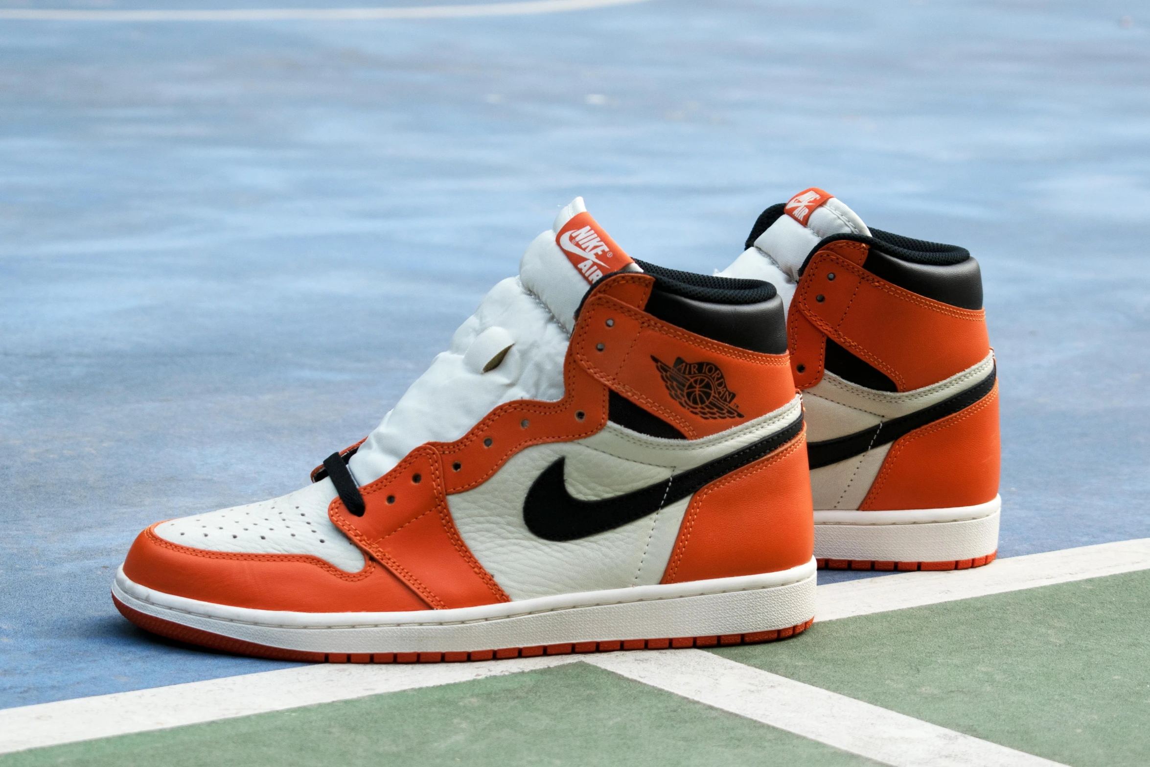 a pair of sneakers sitting on top of a tennis court, air jordan 1 high, orange and white, on display, sports illustrated