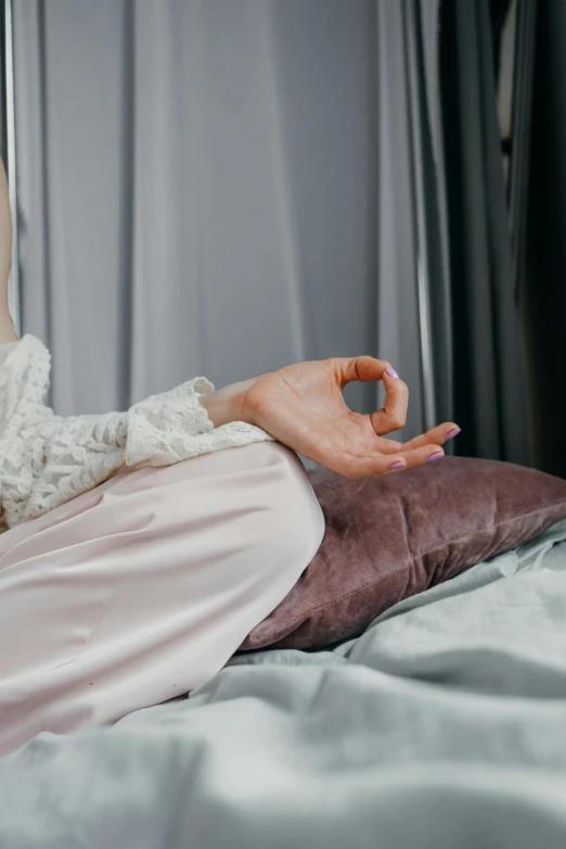 a woman sitting on top of a bed next to a pillow, a statue, inspired by Elsa Bleda, trending on pexels, anjali mudra, hand gesture, soft silk dress, rectangle