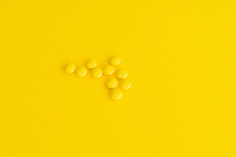 a bunch of yellow pills sitting on top of a yellow surface, a picture, by Emma Andijewska, antipodeans, candy - coated, hyperminimalist, sprites, magnesium