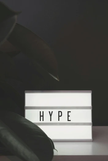 a person standing in front of a sign that says hype, by Byron Galvez, trending on unsplash, hypermodernism, light box, building cover with plant, hibernation capsule close-up, on black background
