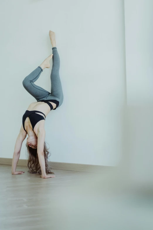 a woman doing a handstand on a hard wood floor, a picture, unsplash, arabesque, low quality photo, wall, anna nikonova aka newmilky, hazy