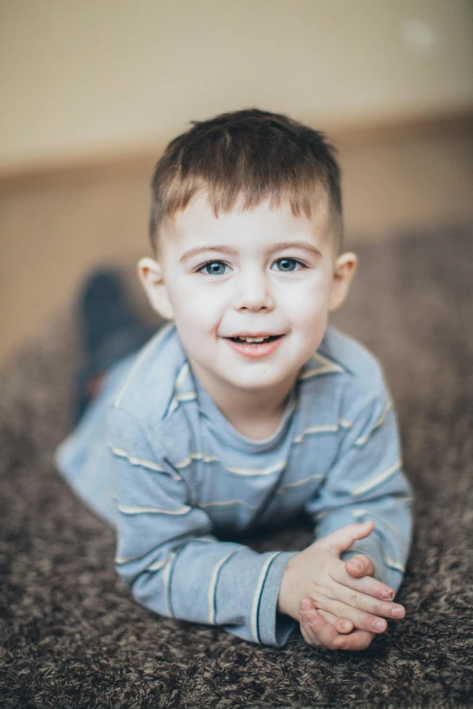 a little boy laying on top of a carpet, a picture, pexels contest winner, lovingly looking at camera, jakub kasper, professionally color graded, full close-up portrait