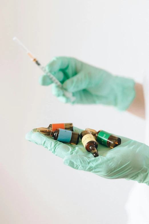 a person in a white shirt and green gloves holding a syssor, a colorized photo, pexels, vibrant vials, iv pole, hemp, instagram post