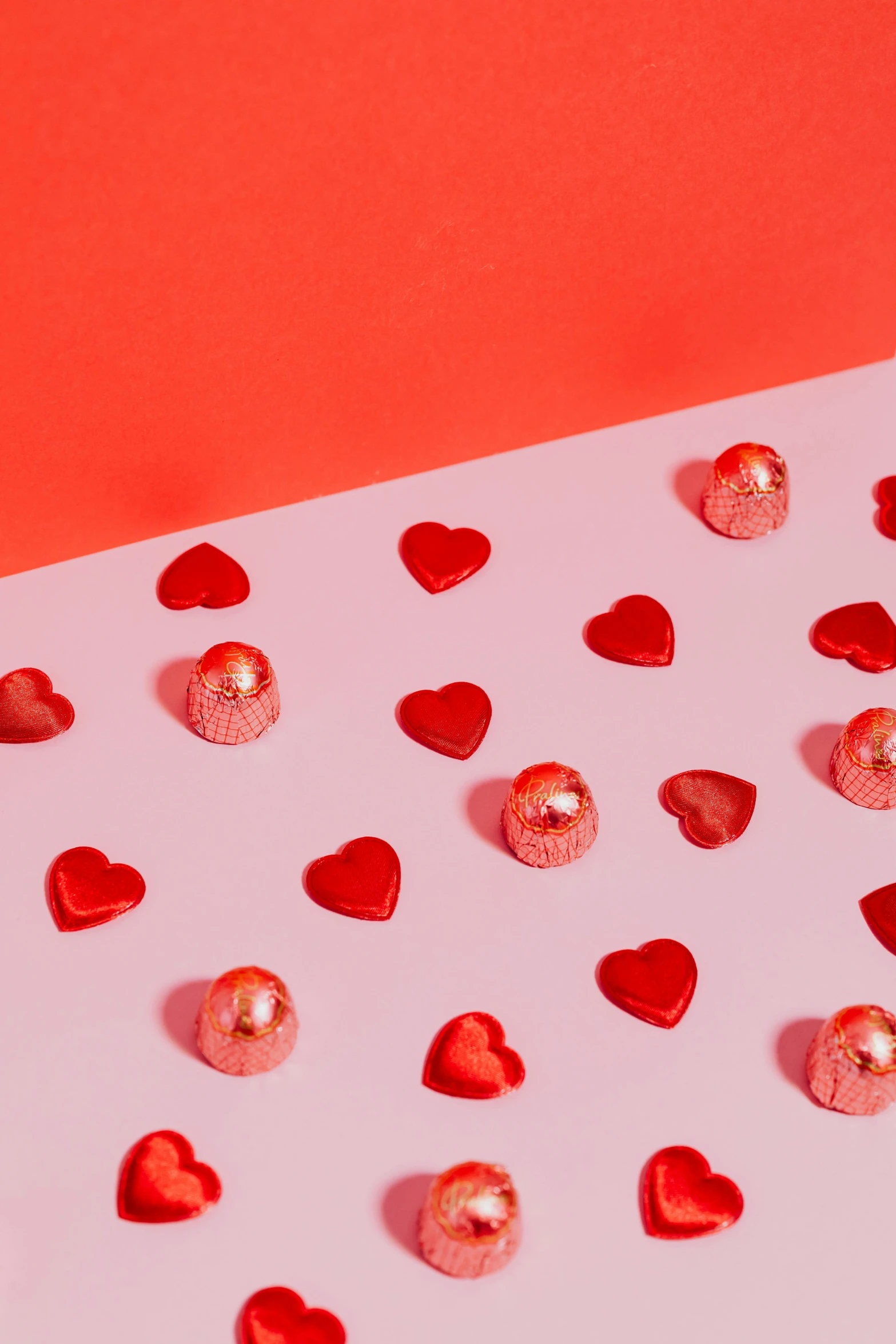 a white table topped with lots of red hearts, in front of an orange background, pearls, product shot, monochromatic red