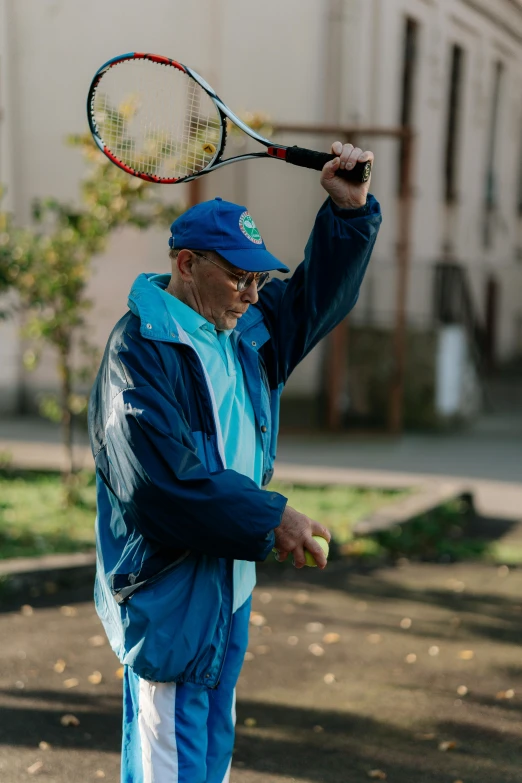 a man holding a tennis racquet on top of his head, a portrait, inspired by Hans Mertens, unsplash, wearing blue jacket, elderly, mid action swing, soviet