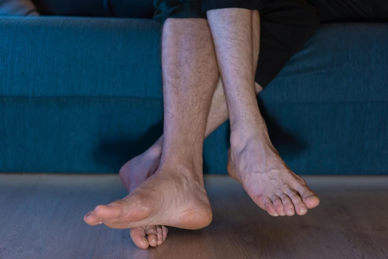 a man sitting on top of a blue couch, by Victorine Foot, unsplash, hyperrealism, feet posing, two legged with clawed feet, paul barson, standing on a shelf
