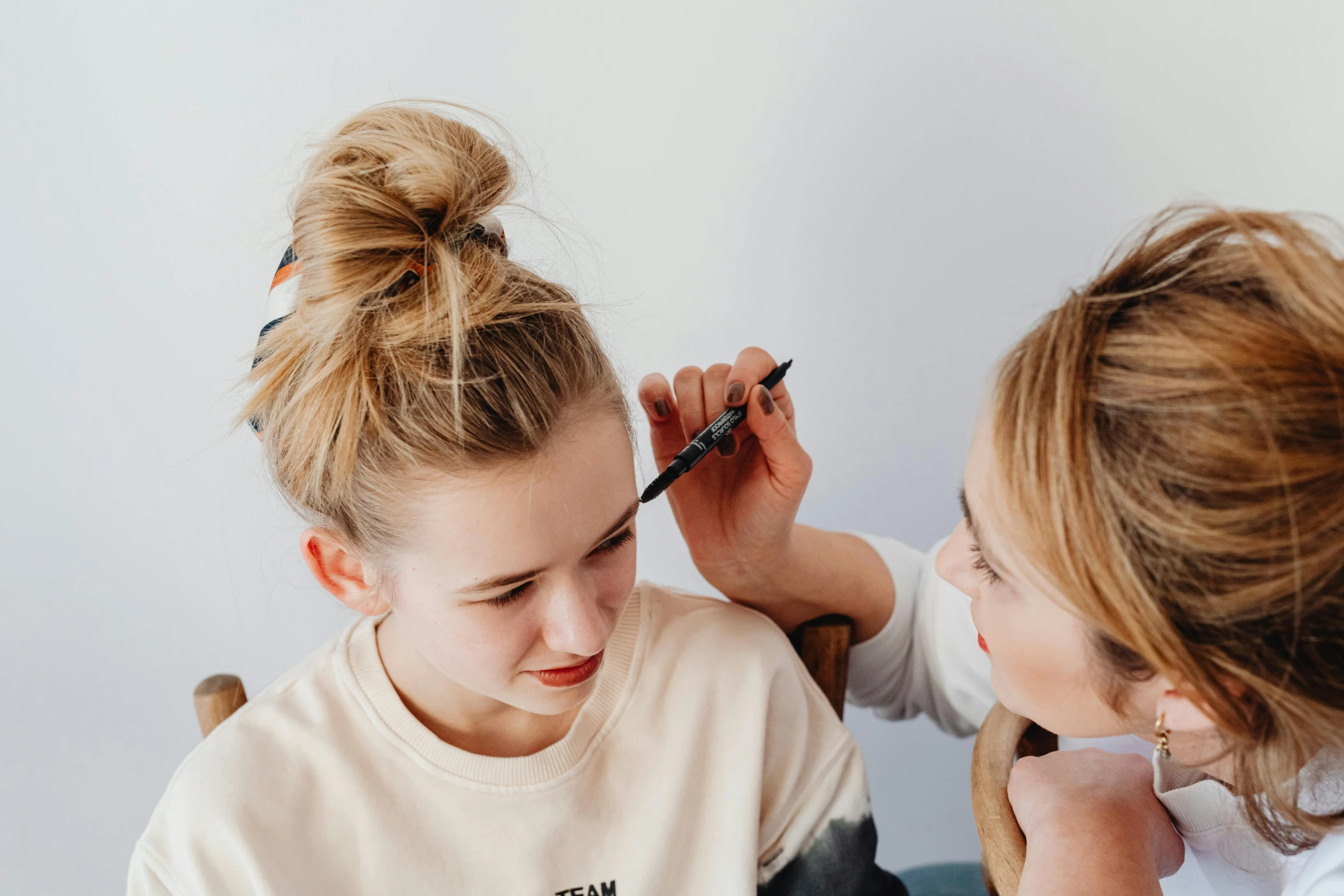 a woman getting her make - up done by a hair stylist, by Grace Clements, trending on pexels, teenage girl, extremely long forehead, eva elfie, looking her shoulder