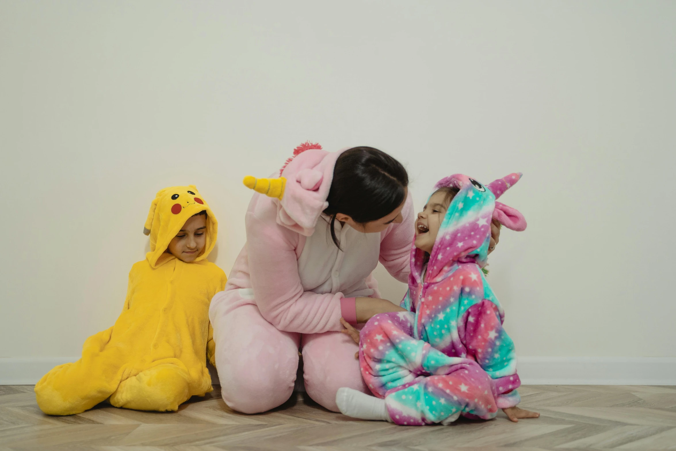 a woman sitting on the floor next to two children in animal onesuits, pexels contest winner, pikachu, gif, softplay, profile image