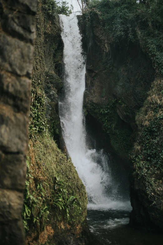 a man standing in front of a waterfall, hurufiyya, swinging on a vine over a chasm, zoomed out, coban, in the center of the image